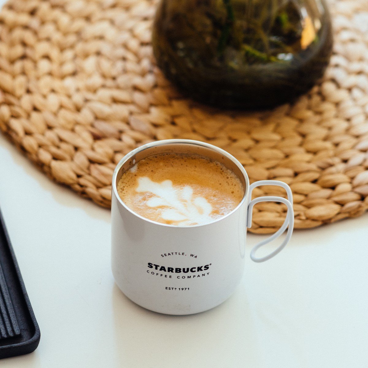 hot latte in white starbucks ceramic mug with logo on white table