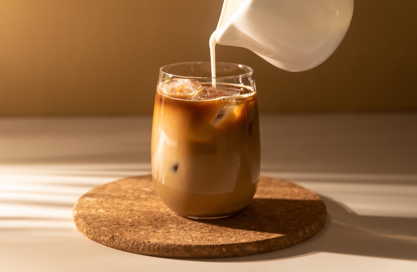 Milk,Cream,Is,Poured,Into,A,Iced,Cold,Brew,Coffee.