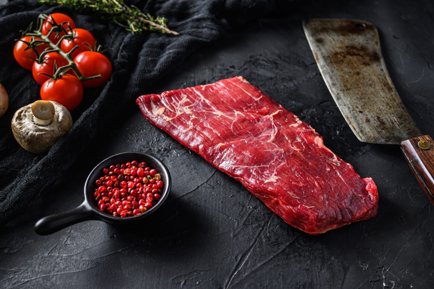 raw flank steak with butcher knife