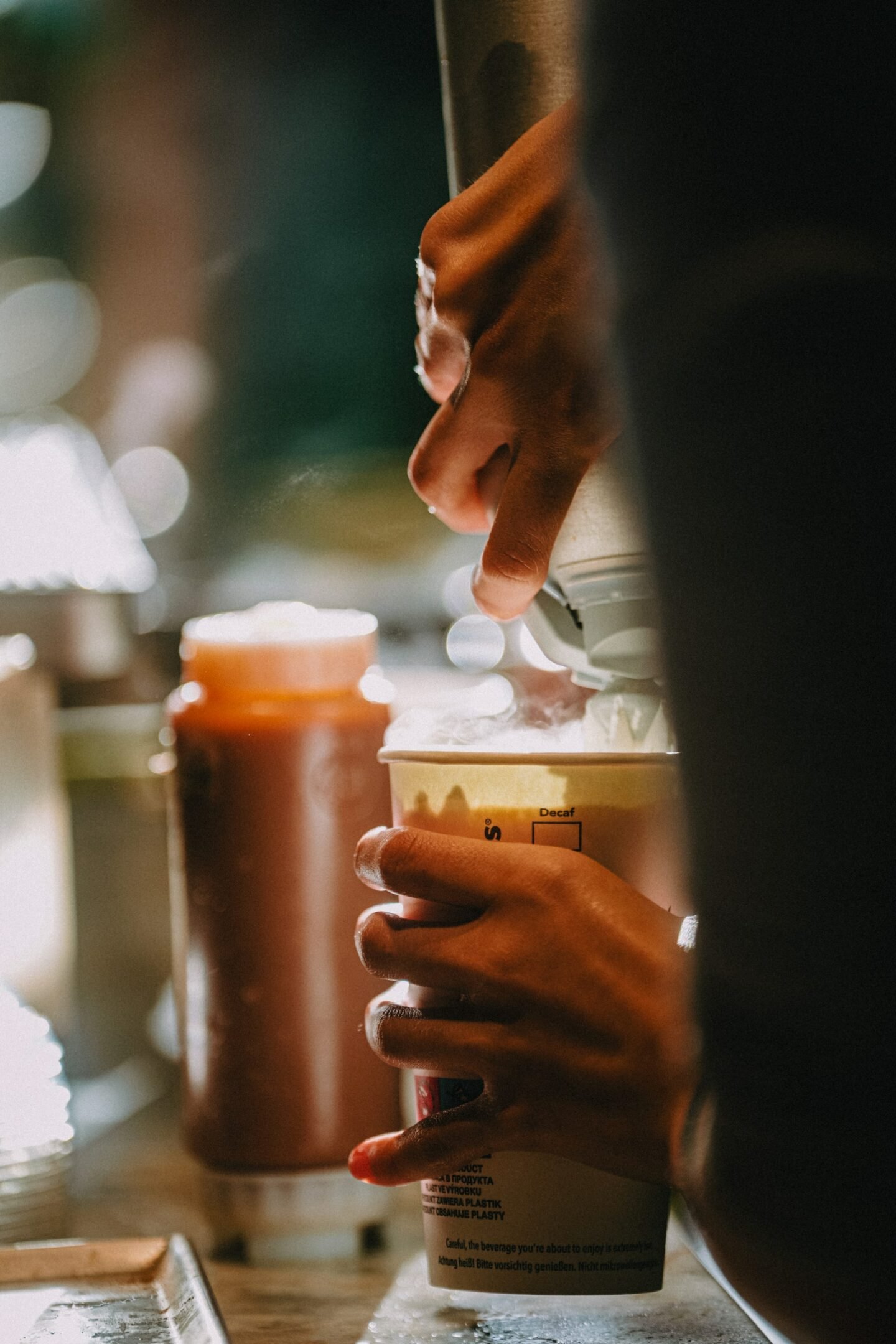 starbucks barista holding cup while adding whipped cream on top of drink