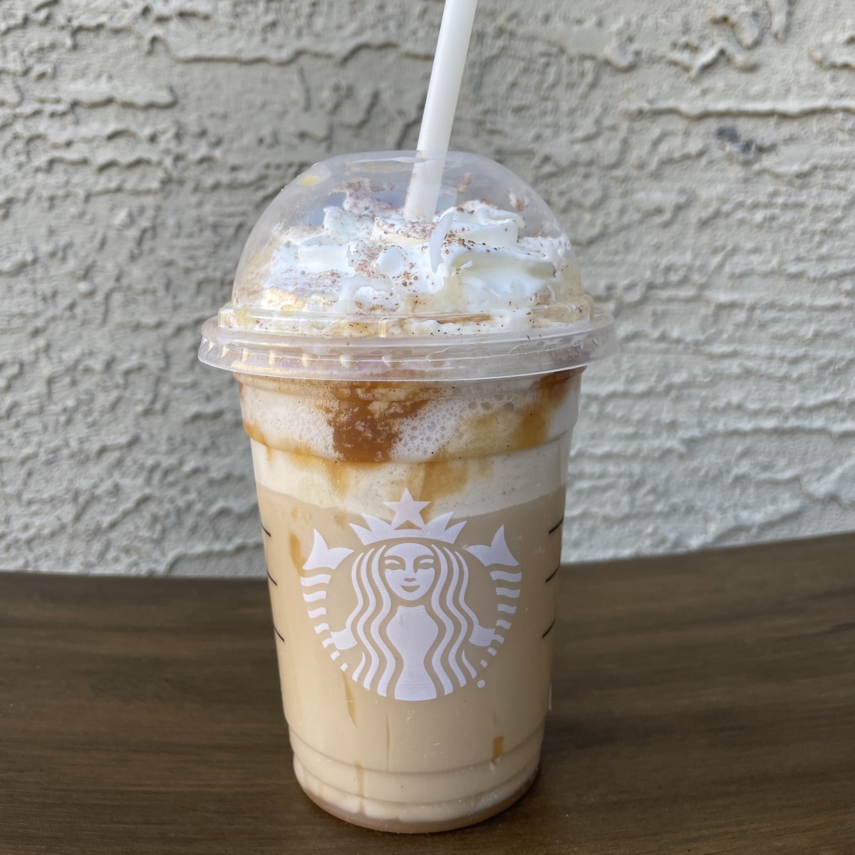 starbucks funnel cake frappuccino in transparent disposable cup on wooden table
