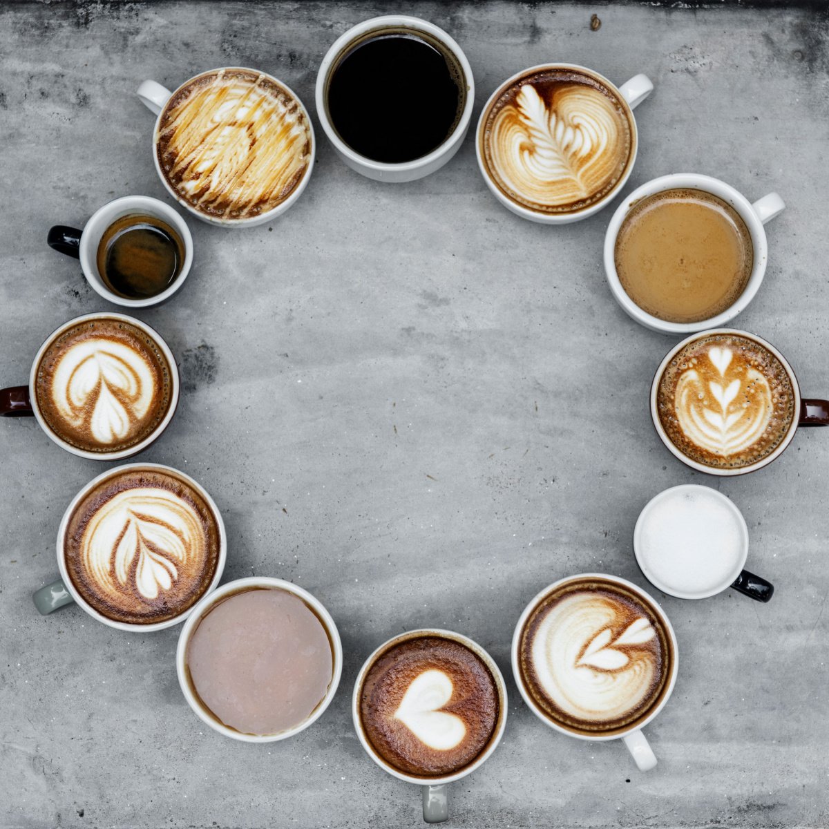 top view of various types of coffees in mugs arranged in a circle on surface