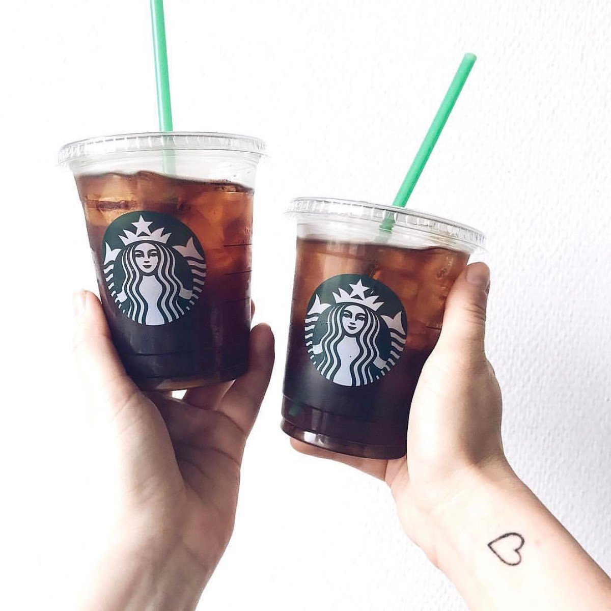 two hands holding up starbucks cold brew in transparent cups