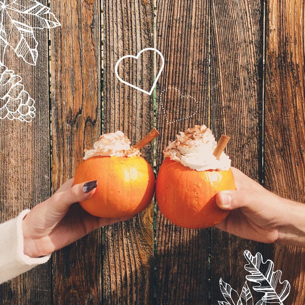 two hands raising cups of starbucks pumpkin spice lattes in small pumpkins