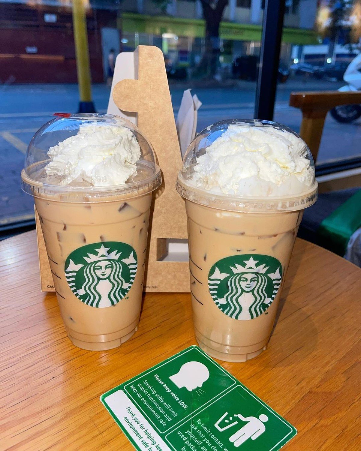 two orders of starbucks iced white chocolate mocha in transparent disposable cups on wooden table