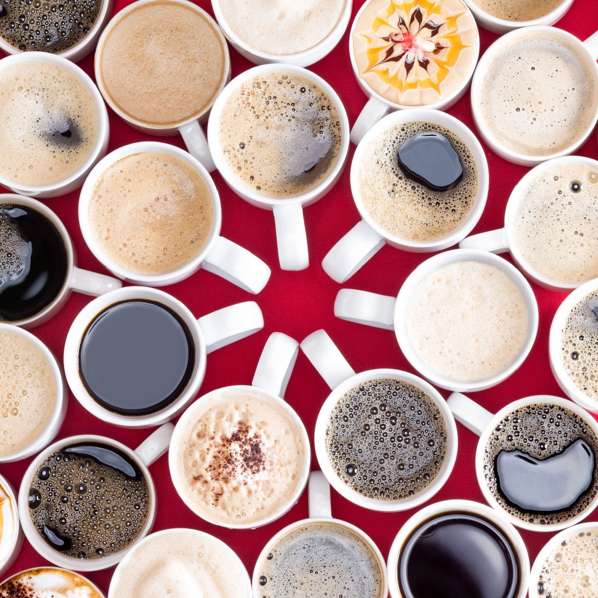 various types of brewed coffee and flavors in identical white ceramic mugs on red surface