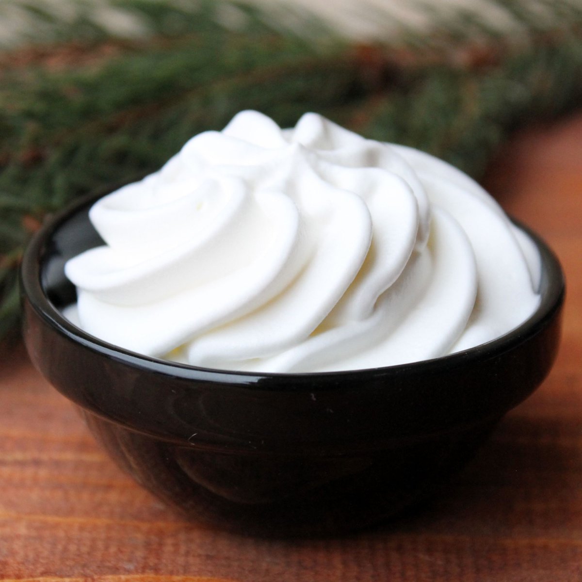 whipped cream in small black bowl on wooden table