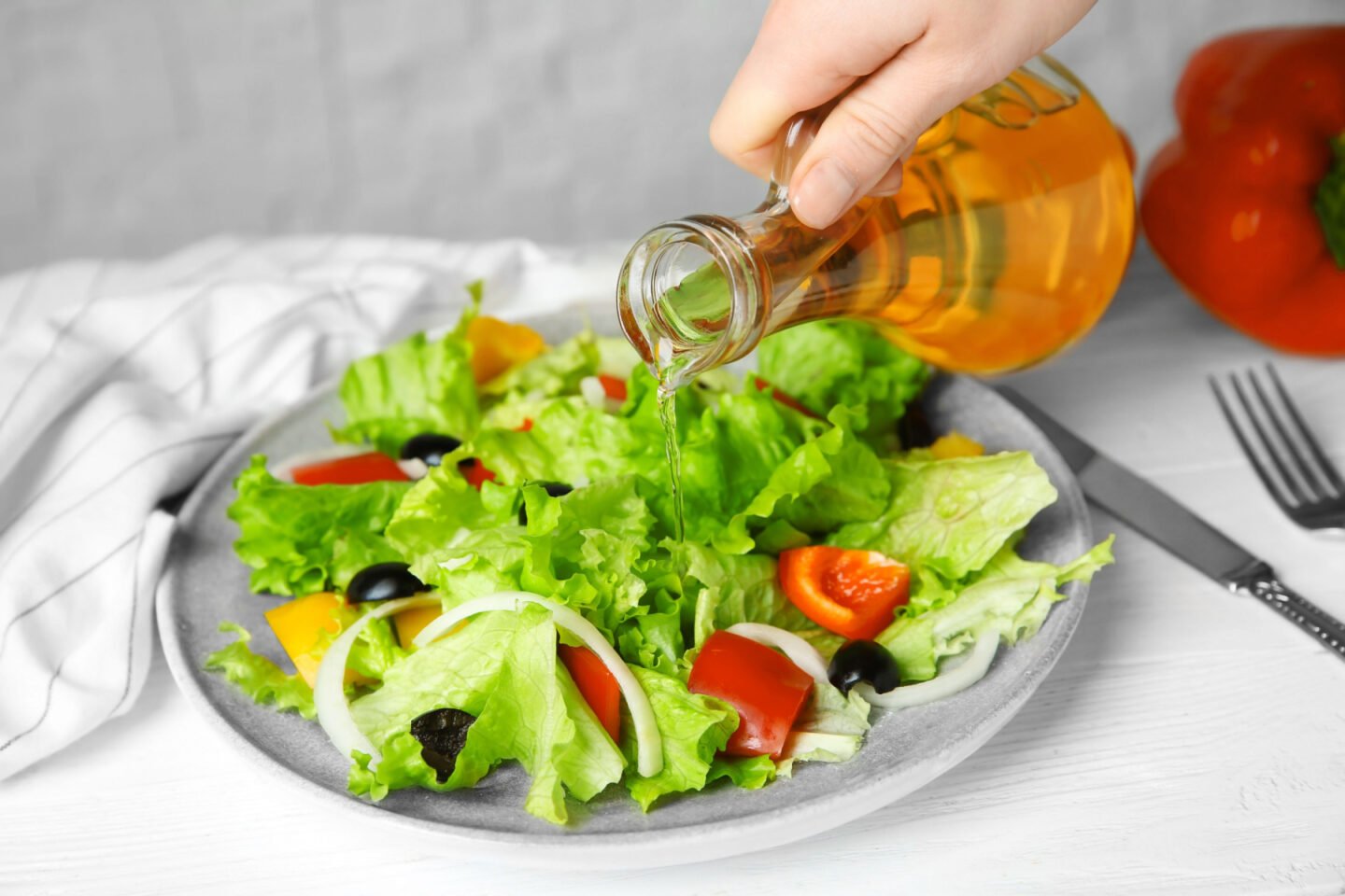 woman adding apple cider vinegar to salad