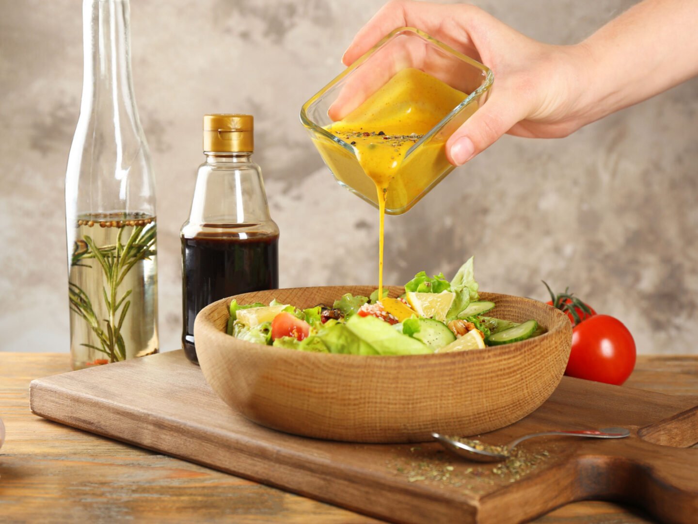 woman pouring honey mustard into salad