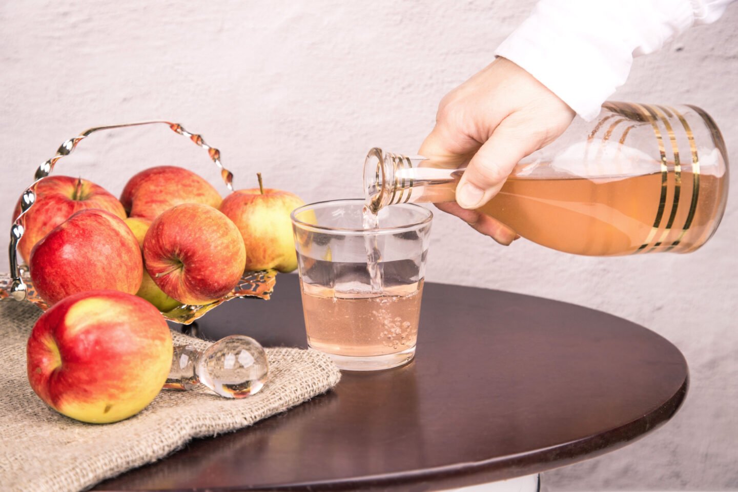 woman pours apple cider vinegar into glass