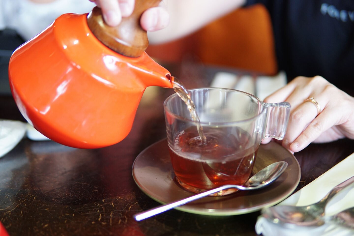 woman pours earl grey tea into glass cup