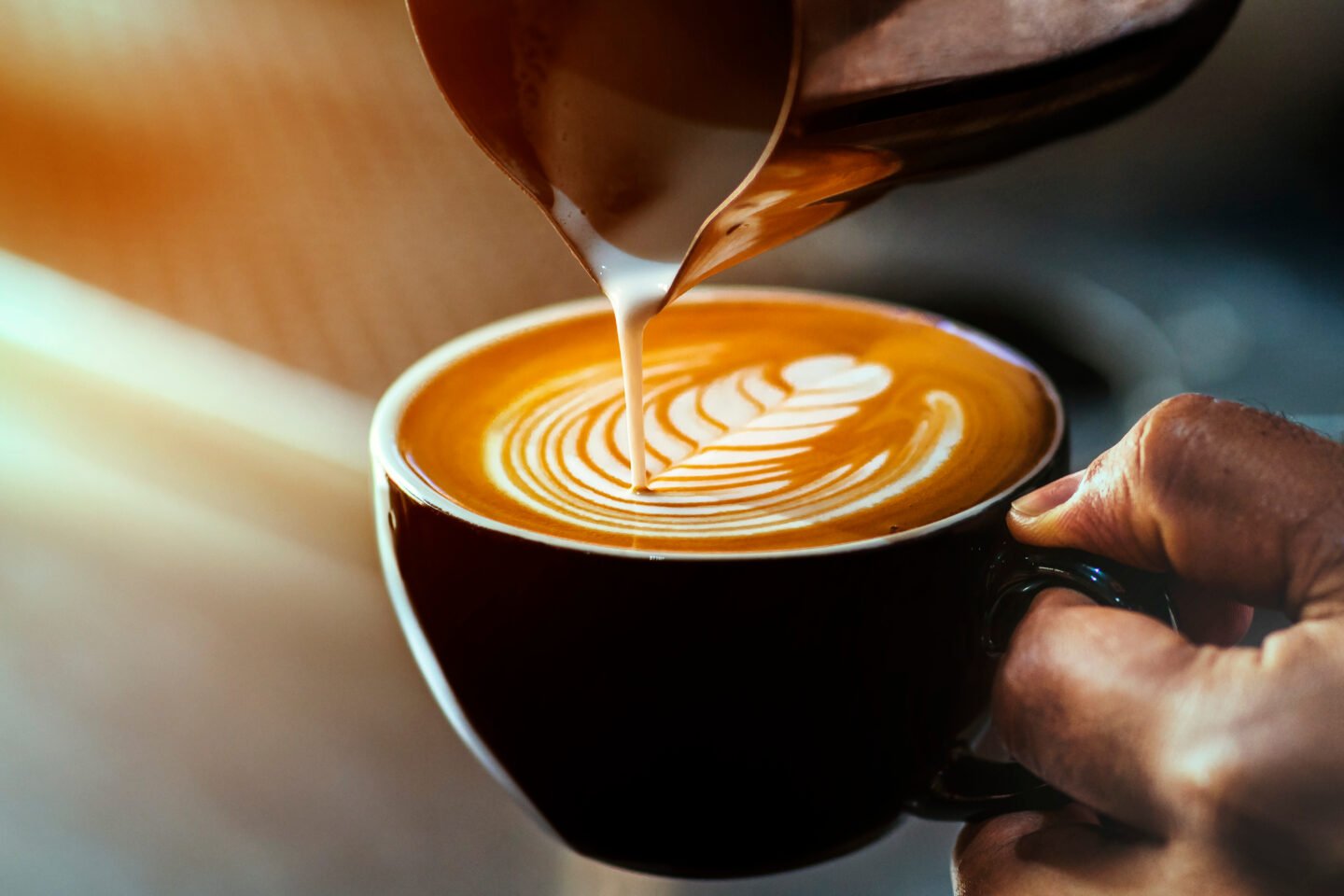 a-black-cup-with-latte-as-the-barista-makes-latte-art