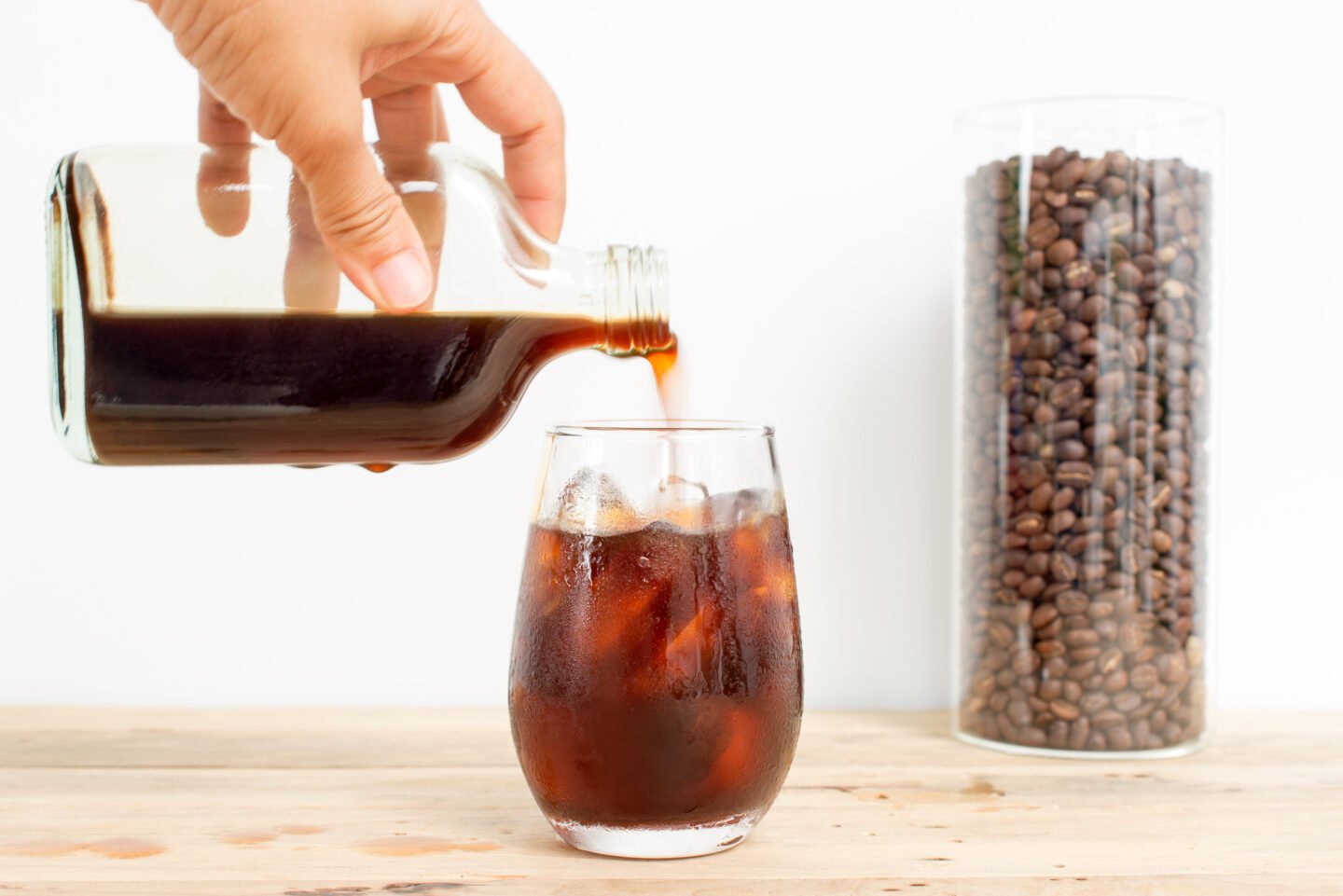 a-bottle-of-cold-brew-being-poured-into-a-glass-with-ice