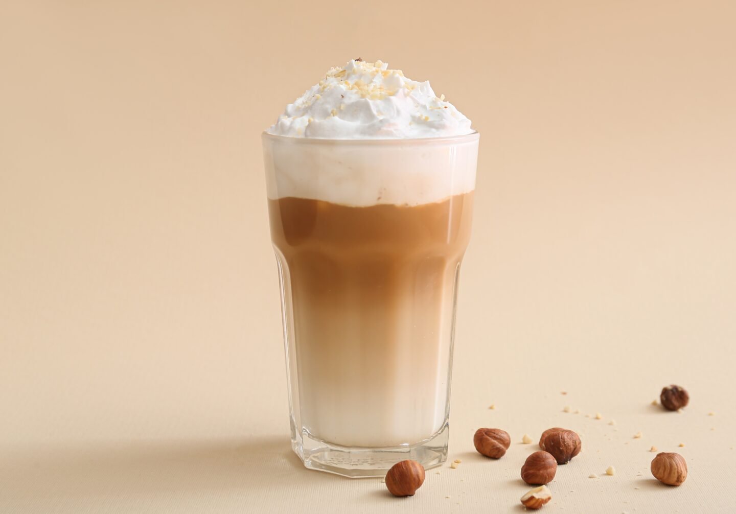 a-glass-of-latte-with-cream-toppings-on-a-beige-background