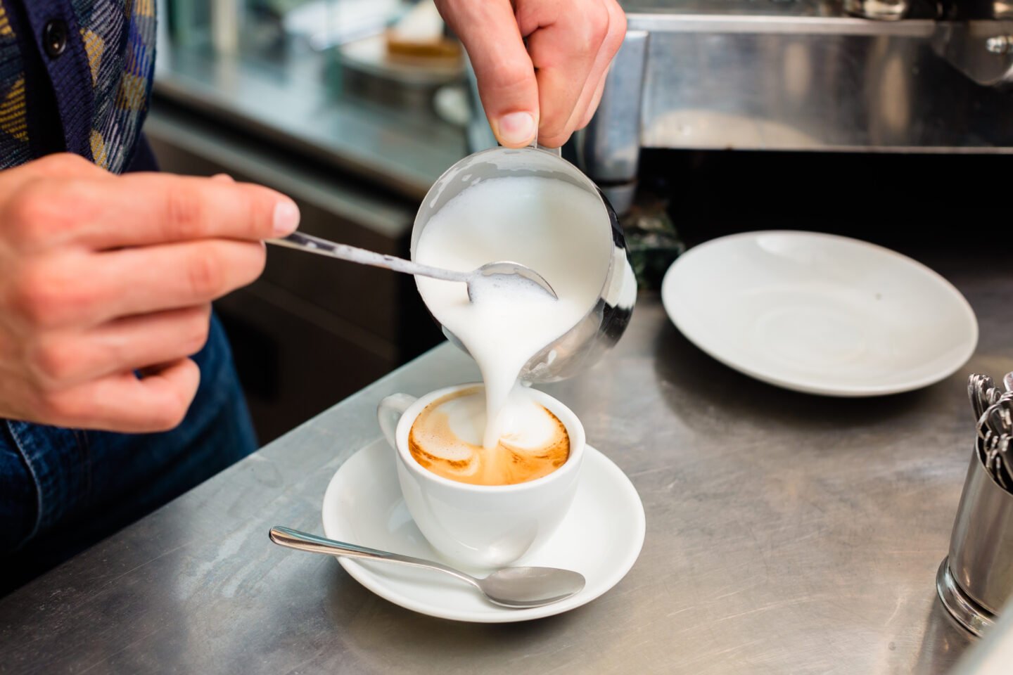 barista-in-cafe-pouring-milk-froth-in-a-cup