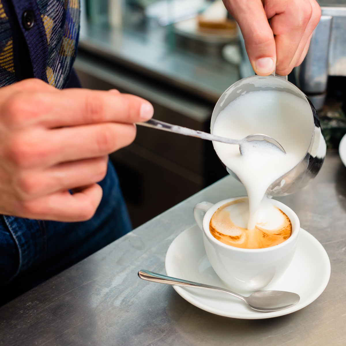 barista-preparing-proper-cappuccino-pouring-milk-froth-in-a-cup