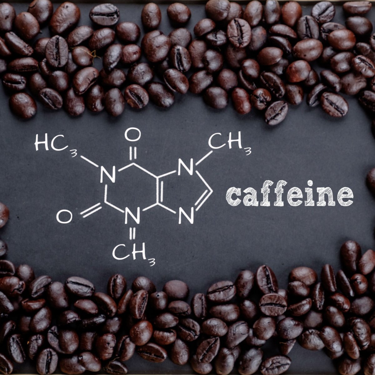caffeine word and chemical structure written on blackboard surrounded by coffee beans