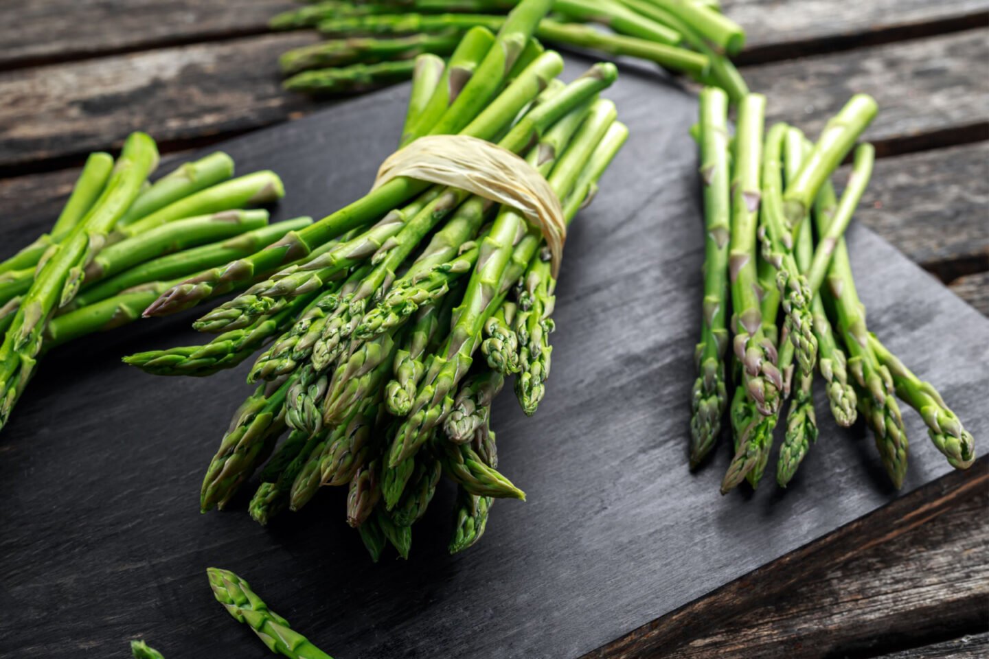 fresh asparagus stalks on a dark board