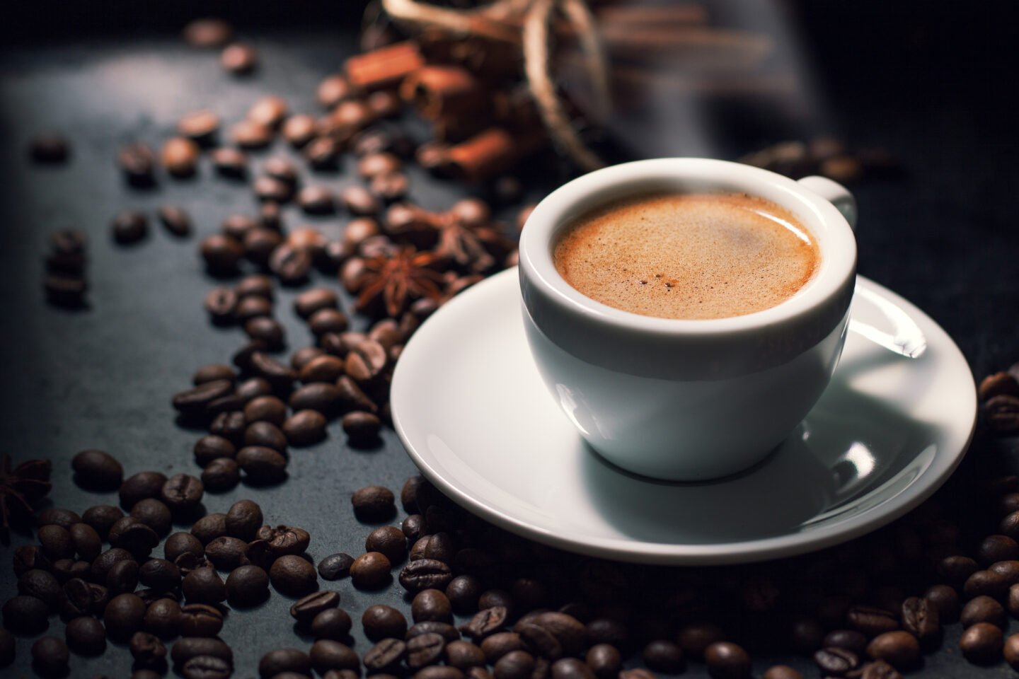 fresh-tasty-espresso-cup-of-hot-coffee-with-coffee-beans-on-dark-background
