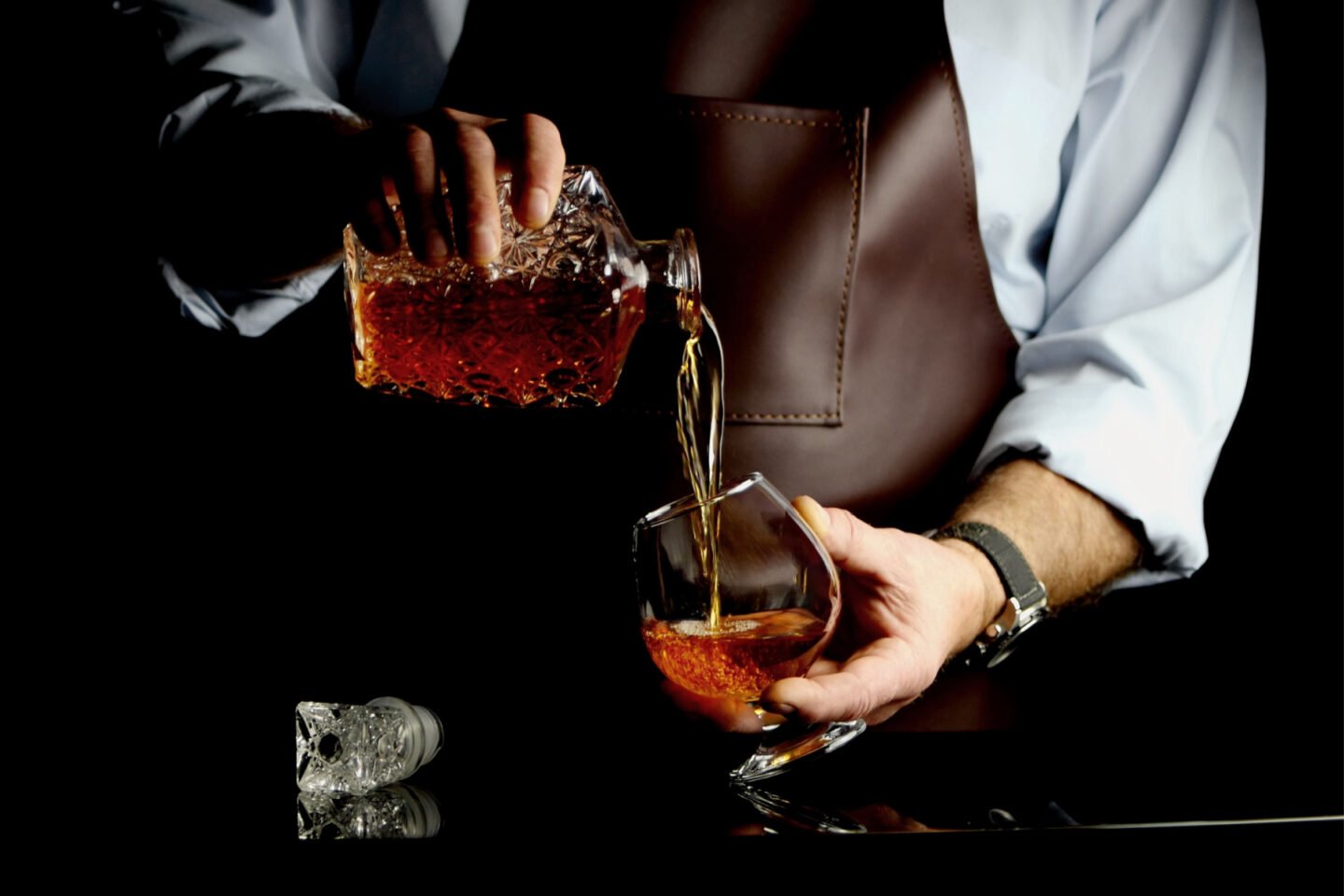 man pours brandy into glass