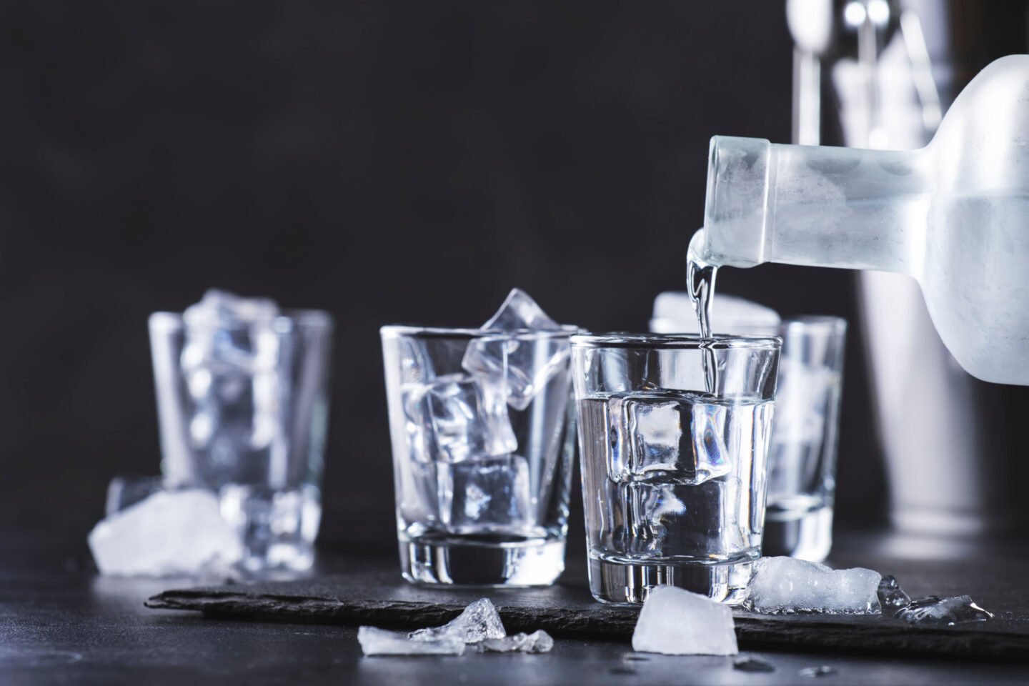 pouring vodka into shot glasses with ice