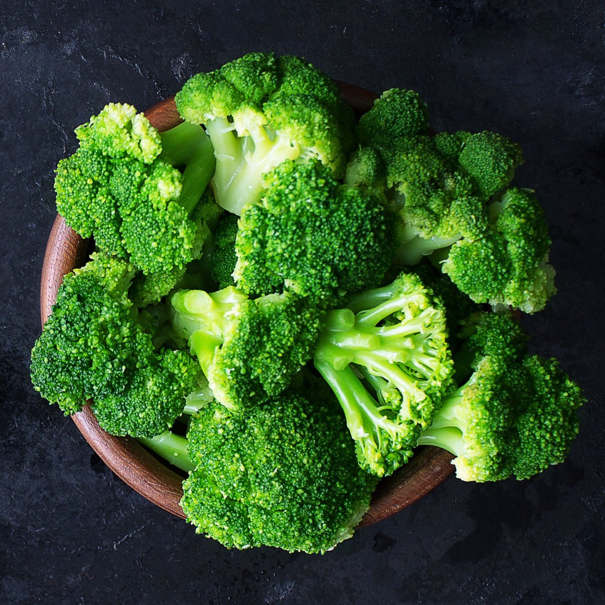 raw broccoli heads in a wooden bowl