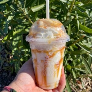 starbucks butterbeer frappucino resting on hand with leaves in background
