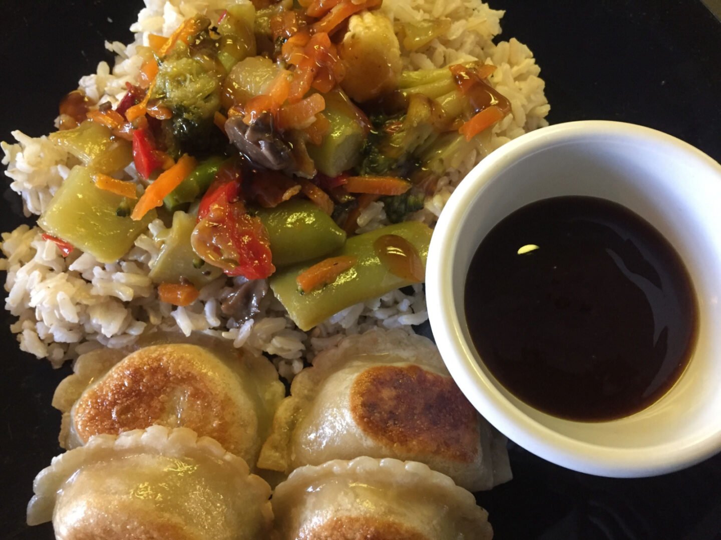 stirfried veggies on rice with dumplings