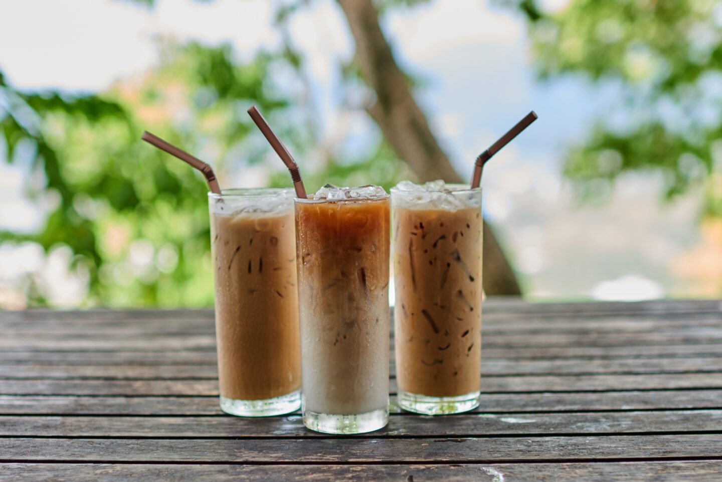three-glasses-of-iced-coffee-with-straws-on-a-wooden-table