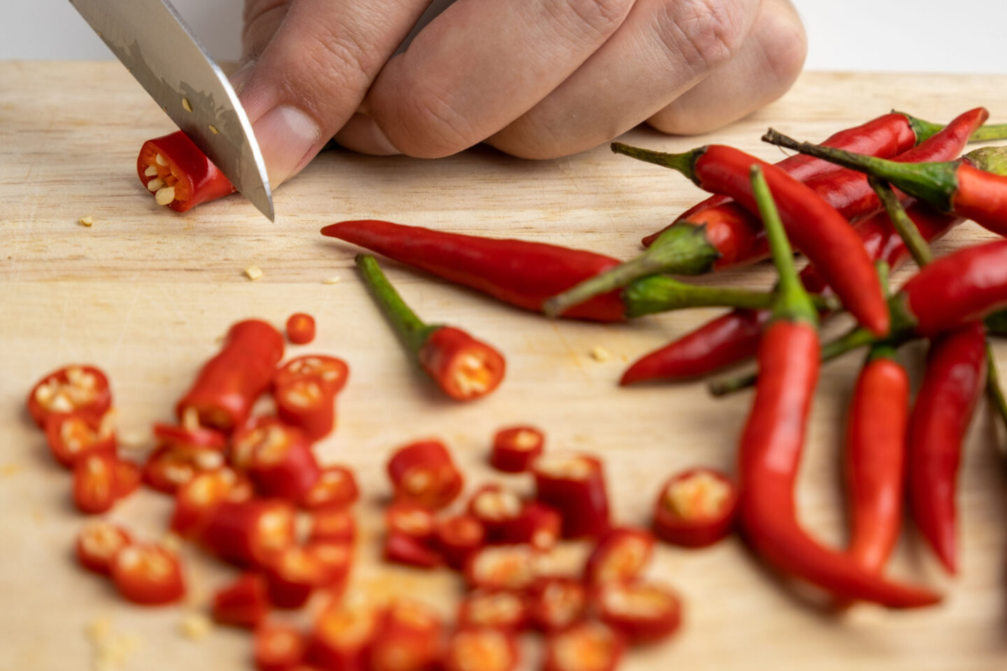 woman cutting chili peppers for cooking