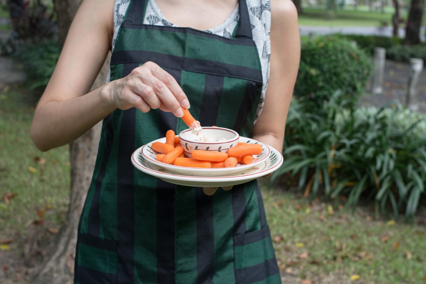 woman dipping baby carrots into ranch dressing