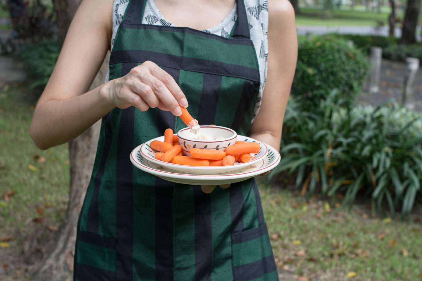 woman dipping baby carrots into ranch dressing