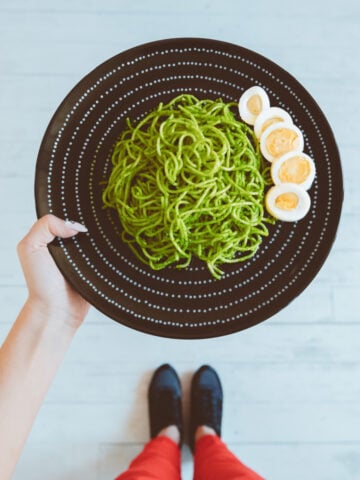 Woman Holding A Plate Of Pesto Pasta 360x480