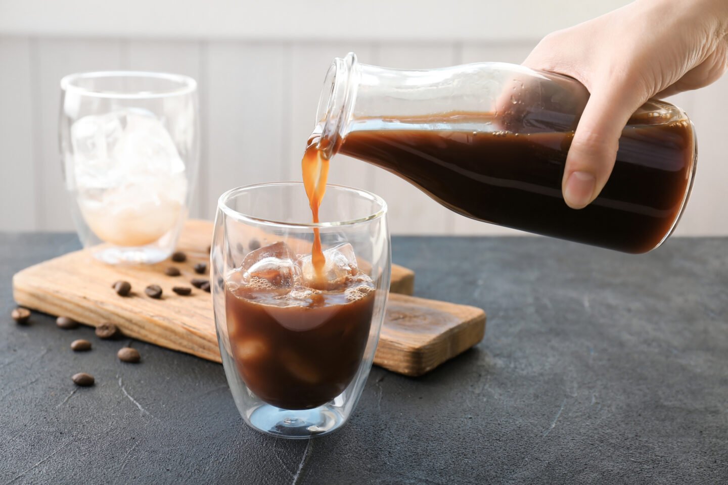 woman-pouring-cold-brew-coffee-into-glass-on-table