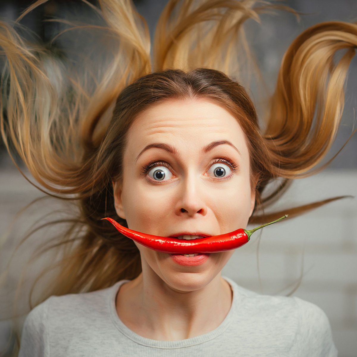 woman with red chili pepper in her mouth
