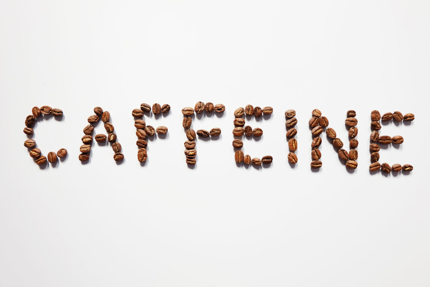 Letter,Of,Caffeine,Arranged,With,Coffee,Beans,On,White,Background