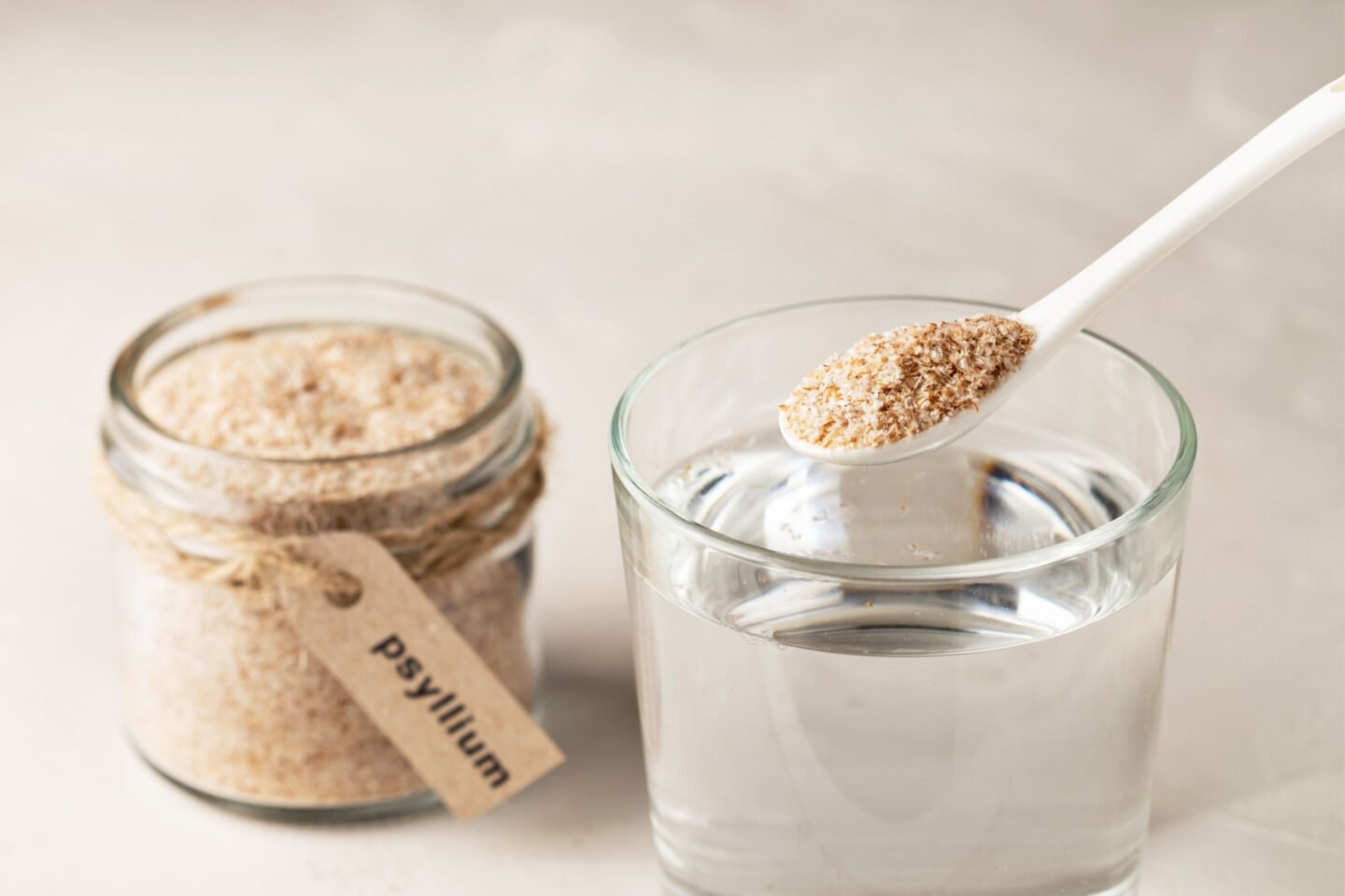 a jar and teaspoon of psyllium husk and a glass of water
