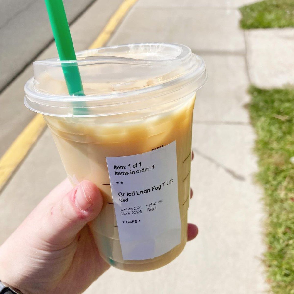 close up on starbucks iced london fog tea latte held on sidewalk