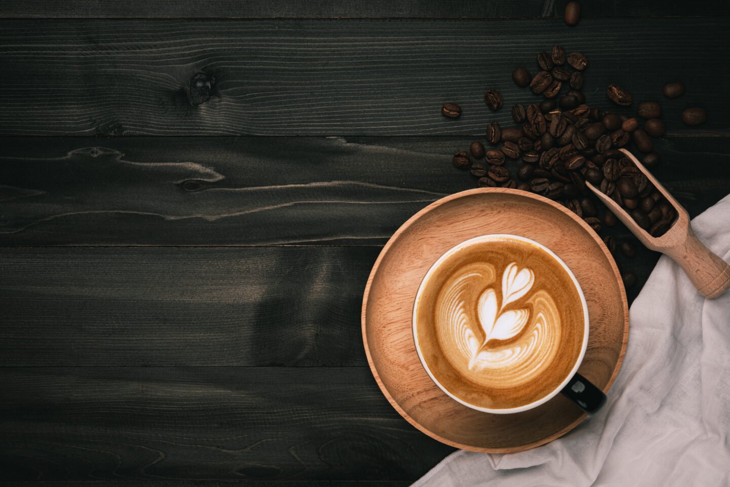 Coffee,Cup,With,Latte,Art,And,Beans,On,Old,Wood