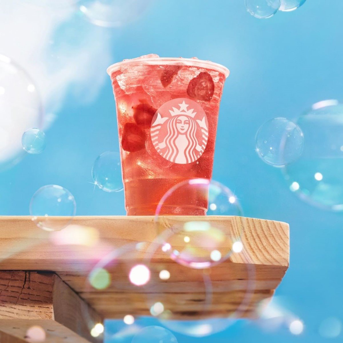 cup of starbucks strawberry acai refresher on wooden surface with bubbles on image