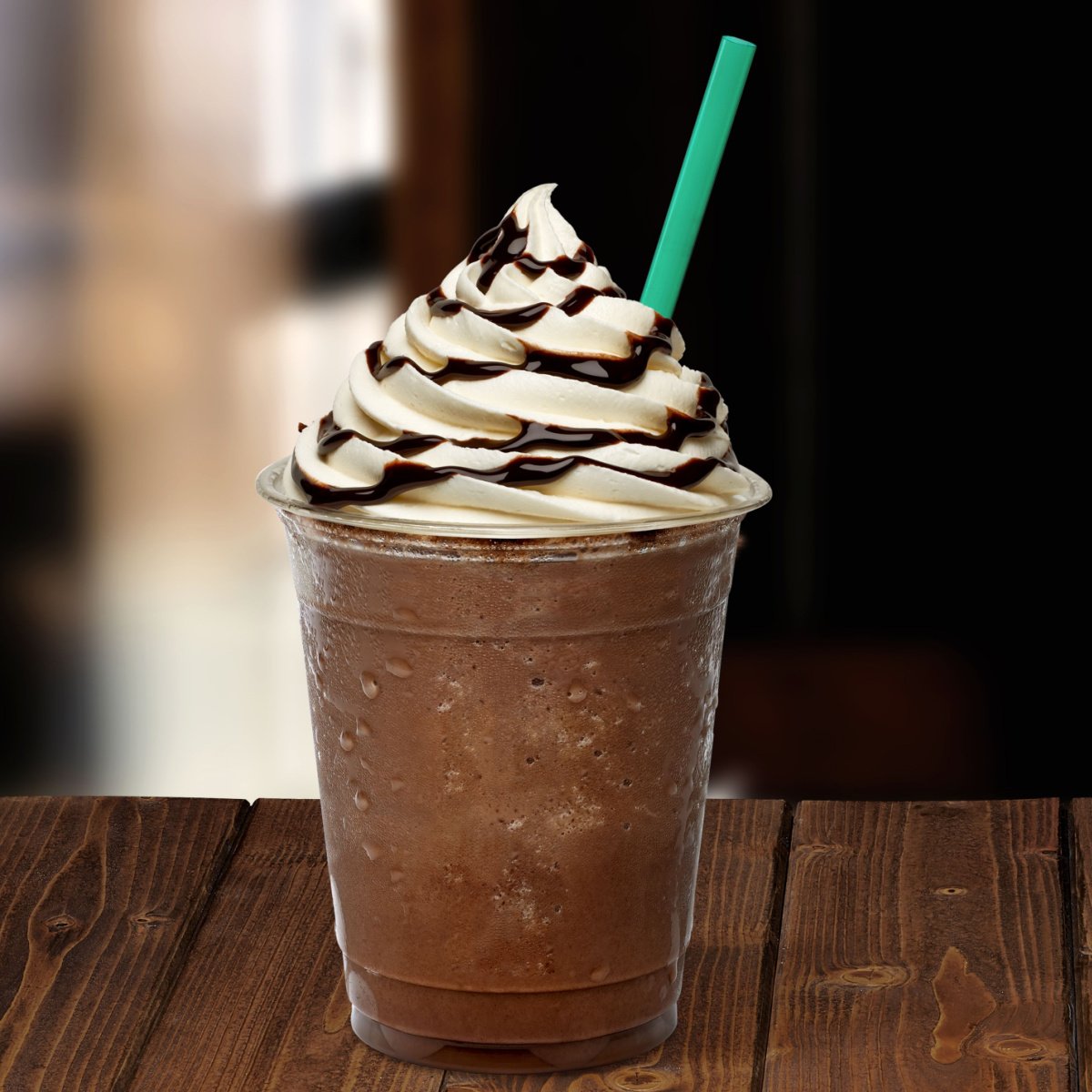 frappuccino in clear plastic takeaway cup with straw on wooden table