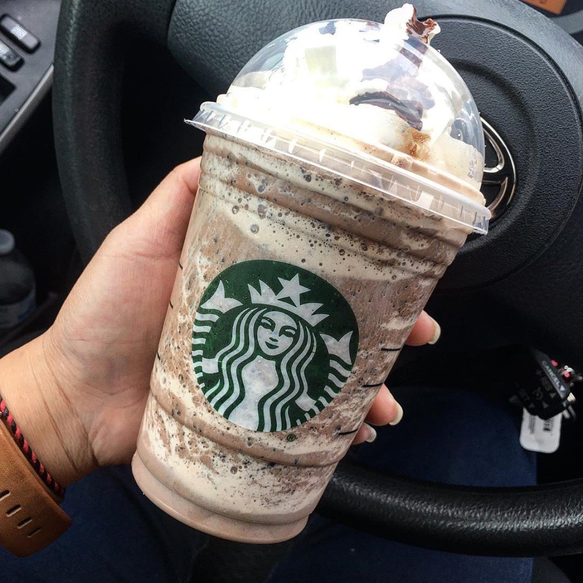 hand holding starbucks double chocolaty chip creme frappuccino in front of steering wheel