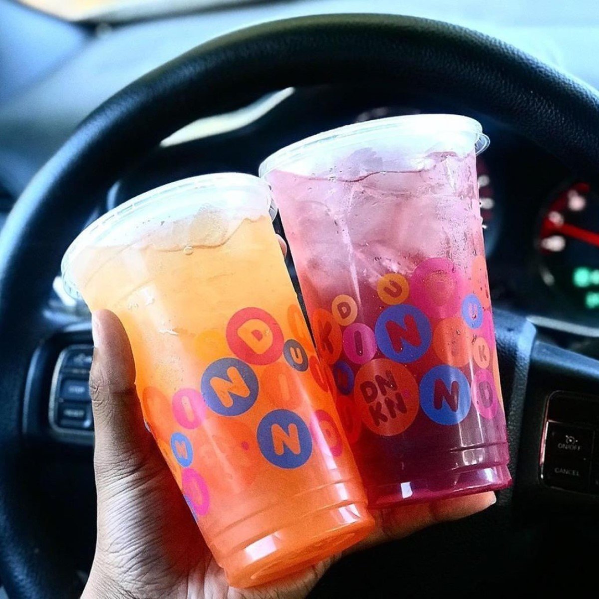 hand holding two cups of dunking refreshers in plastice takeaway cups inside car
