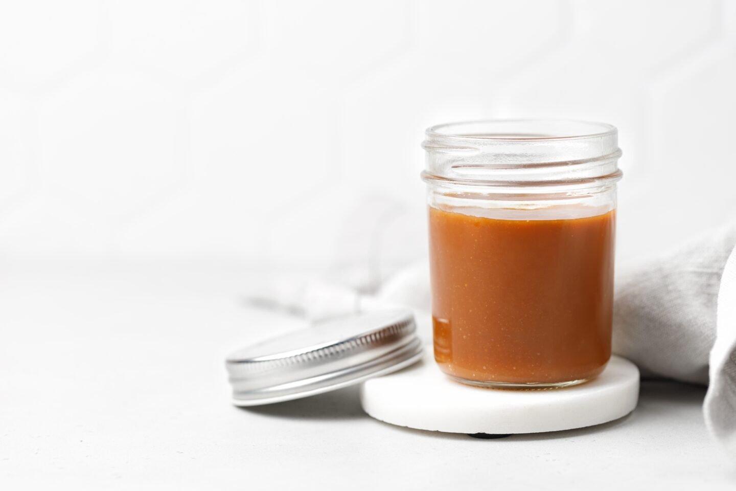 Salted,Caramel,Sauce,In,Glass,Jar,With,Lid,On,Marble