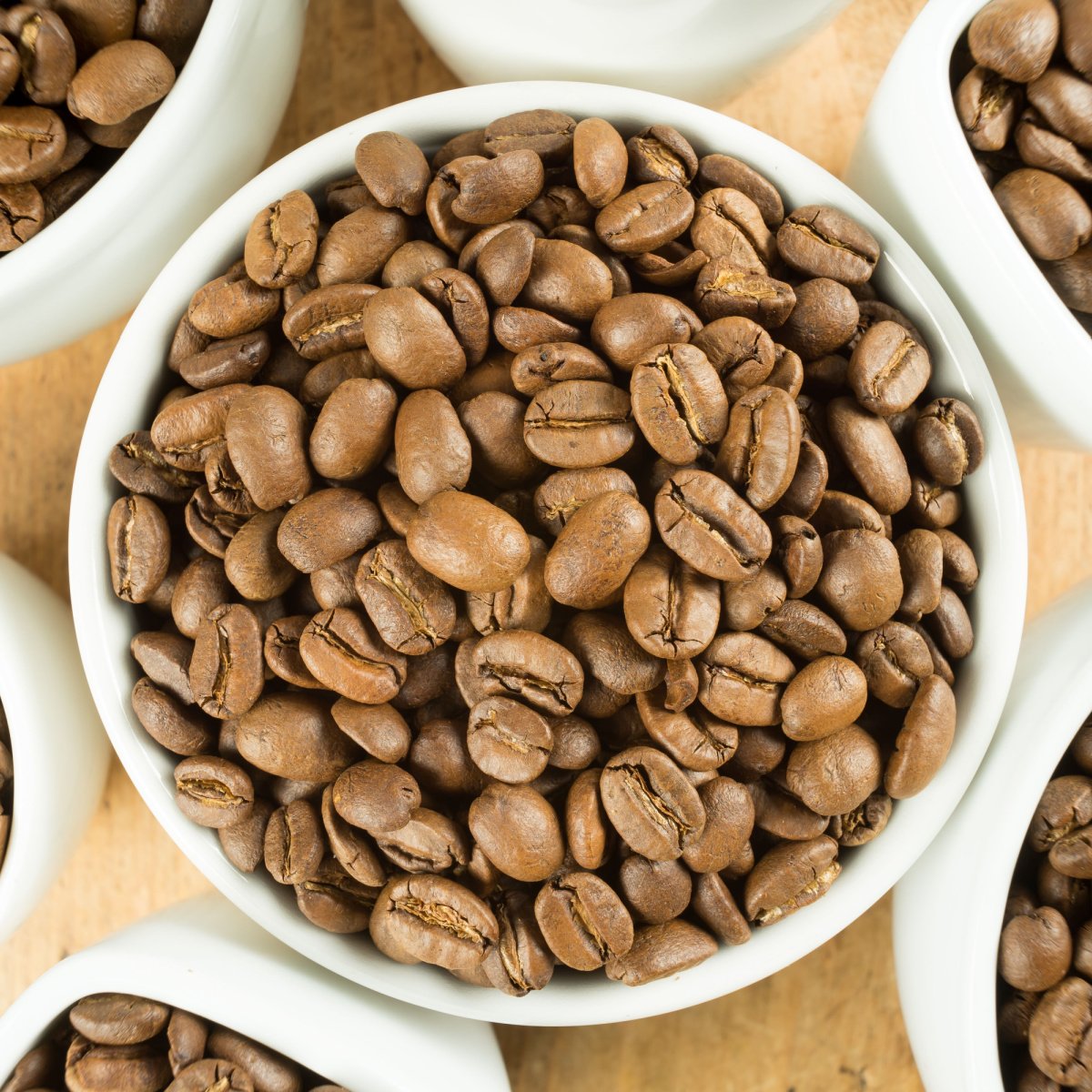 lightly roasted coffee beans in white cup on wooden table