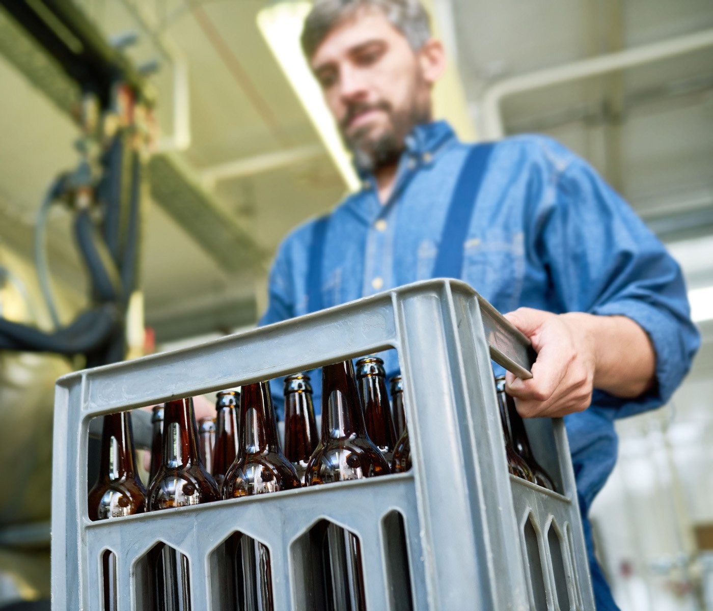 man carrying case of beer bottles