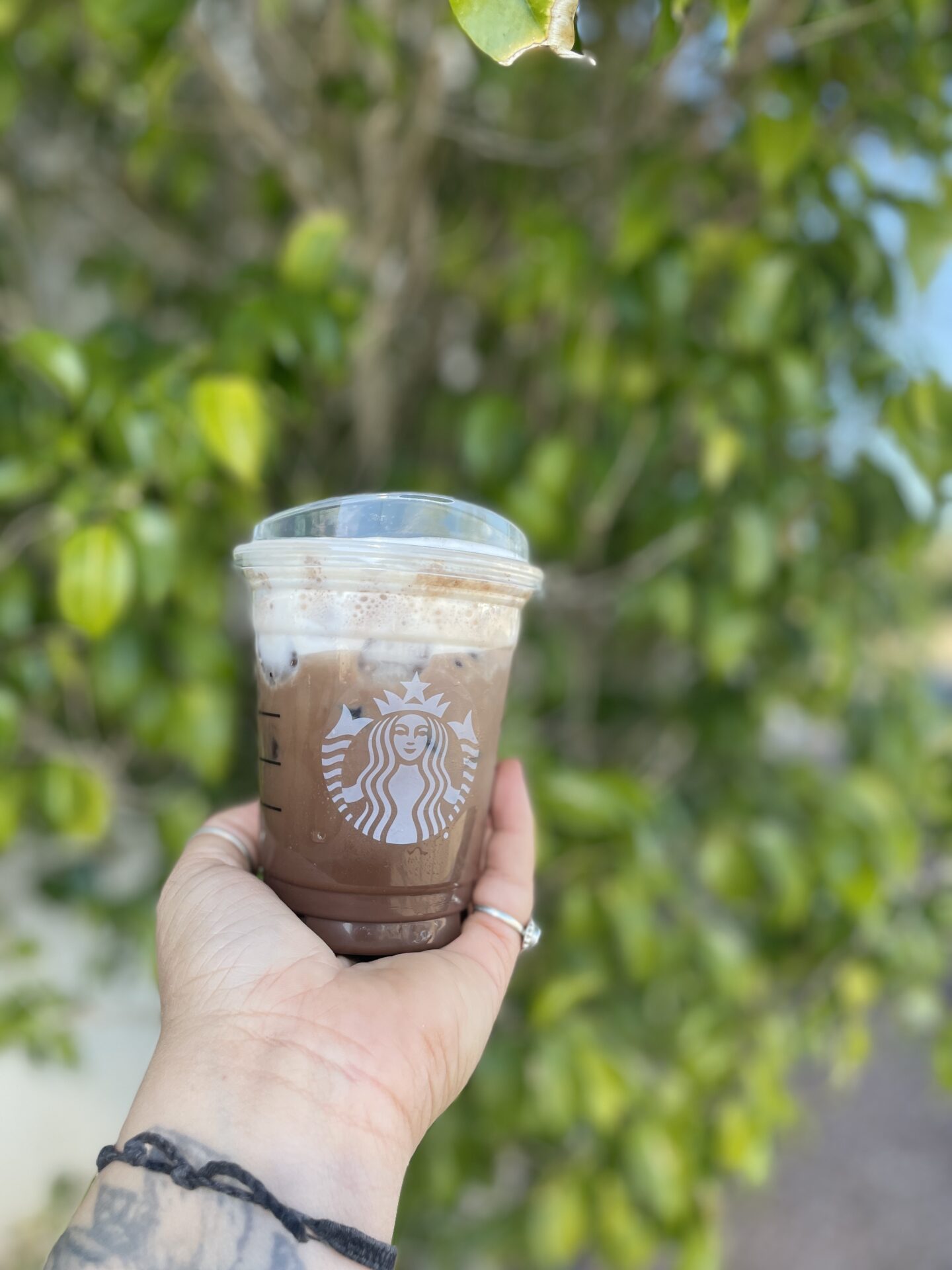 man holding a brownie drink outdoors