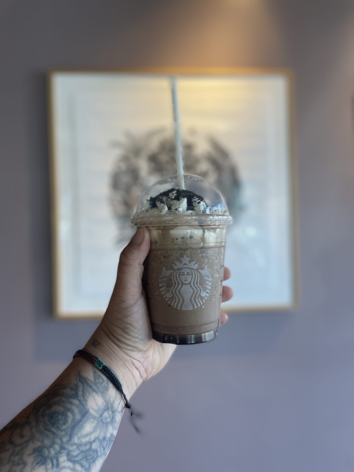 man holding a marble frappe indoors