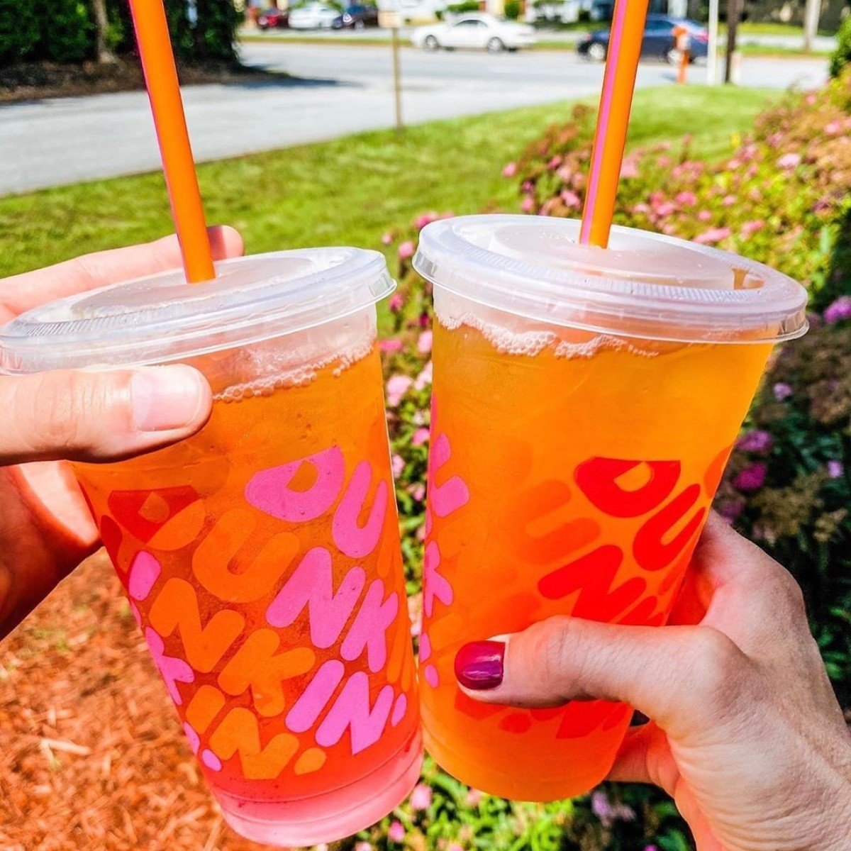 two hands each holding a dunkin refresher in plastic takeaway cups