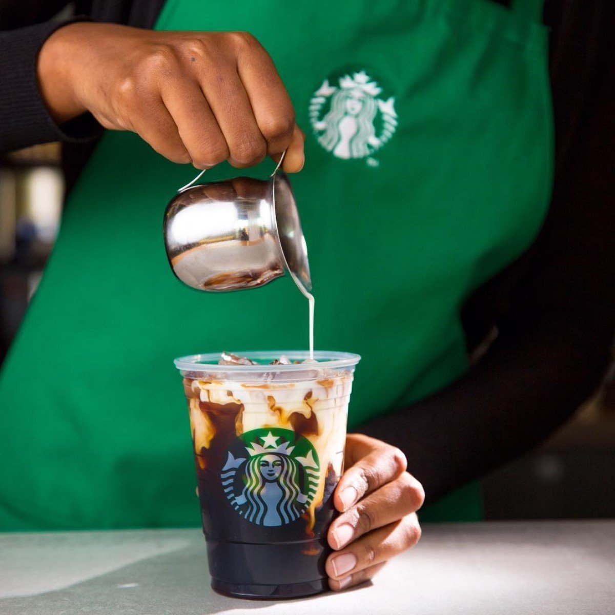 barista pouring milk or cream into starbucks cold brew